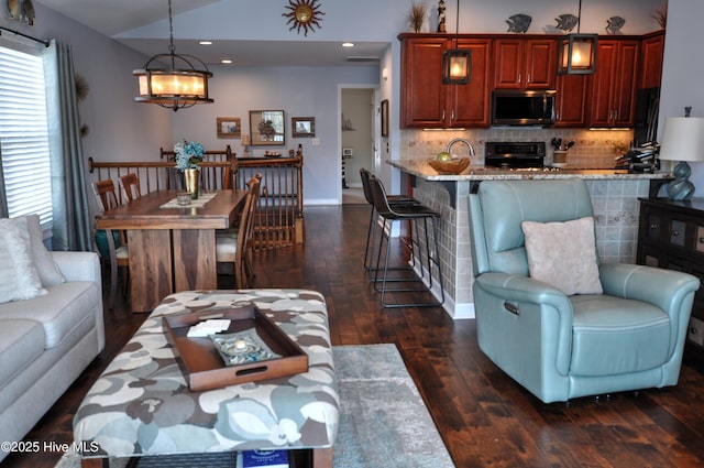 living room featuring baseboards, dark wood finished floors, a chandelier, lofted ceiling, and recessed lighting