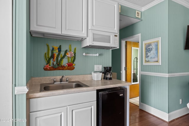 kitchen with ornamental molding, white cabinetry, sink, and dark hardwood / wood-style flooring