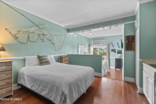 bedroom with wood walls, wood-type flooring, an AC wall unit, a textured ceiling, and crown molding