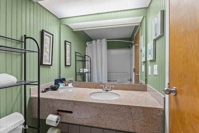 bathroom with vanity, toilet, wood walls, and a shower with curtain