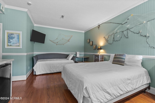 bedroom featuring ornamental molding, a textured ceiling, black refrigerator, and hardwood / wood-style flooring