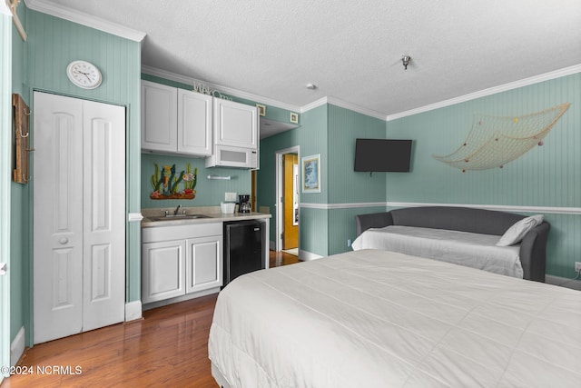 bedroom with a closet, black refrigerator, wood-type flooring, sink, and crown molding