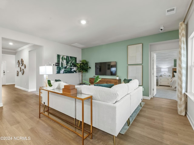 living room with crown molding and light wood-type flooring