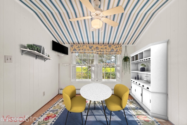 dining area featuring light hardwood / wood-style floors, wood walls, and vaulted ceiling