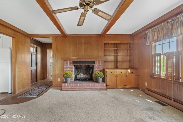 unfurnished living room featuring wooden walls, light carpet, a brick fireplace, built in shelves, and ceiling fan