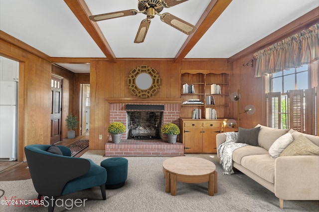 living room featuring a fireplace, hardwood / wood-style floors, ceiling fan, beamed ceiling, and wooden walls