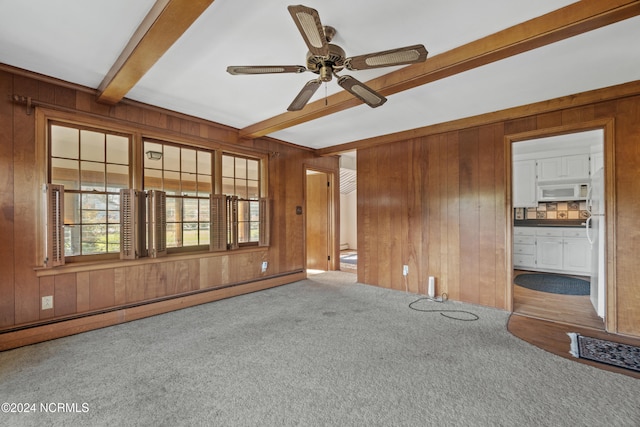 unfurnished living room featuring carpet, wood walls, beamed ceiling, and a baseboard radiator