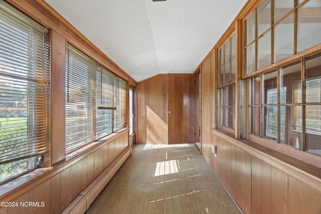 hallway with wood walls, a healthy amount of sunlight, and a baseboard heating unit