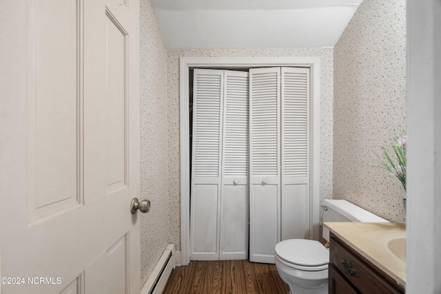 bathroom with a baseboard heating unit, hardwood / wood-style floors, vaulted ceiling, toilet, and vanity