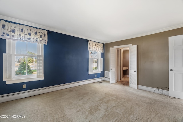 carpeted spare room with baseboard heating, ornamental molding, and a healthy amount of sunlight