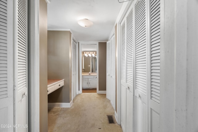 hall with ornamental molding and light colored carpet