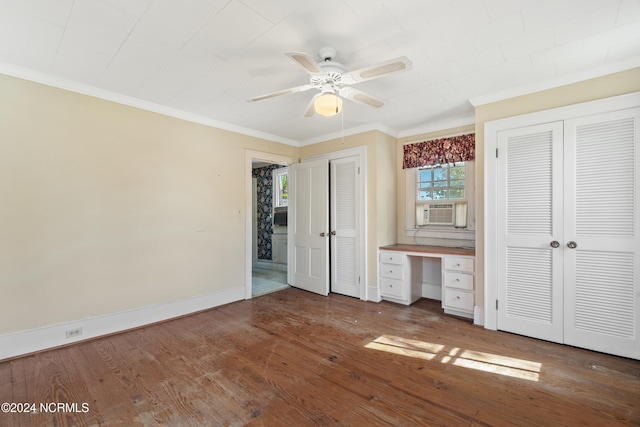 unfurnished bedroom with wood-type flooring, built in desk, cooling unit, ceiling fan, and ornamental molding