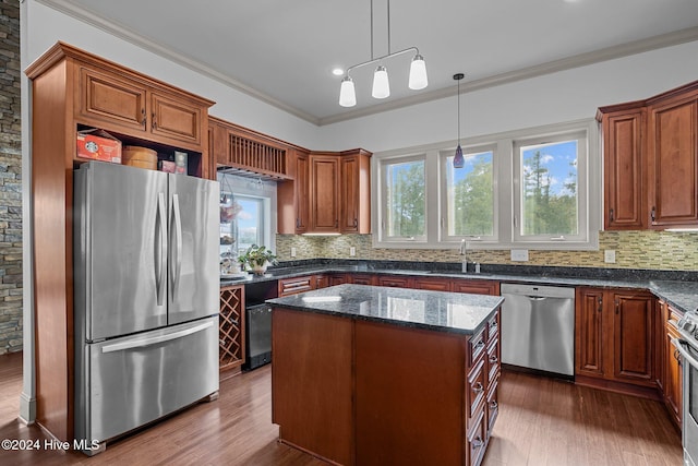 kitchen featuring stainless steel appliances, sink, a center island, tasteful backsplash, and hanging light fixtures