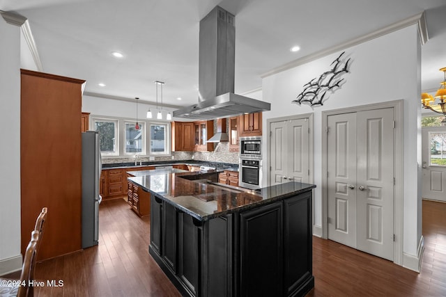 kitchen with decorative light fixtures, a center island, island exhaust hood, dark stone counters, and appliances with stainless steel finishes