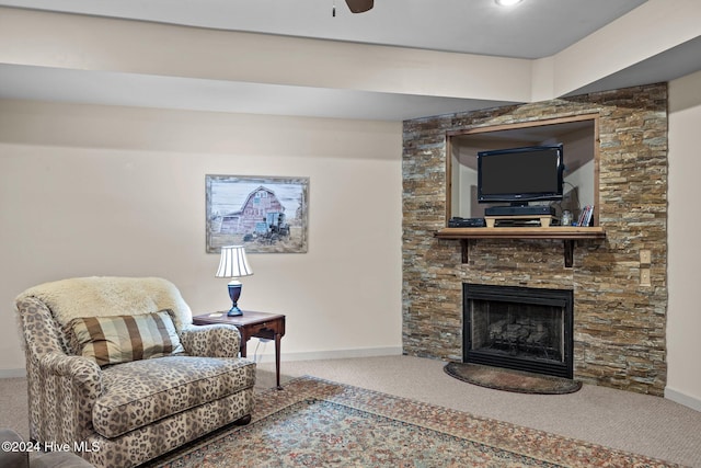 living room featuring a fireplace, ceiling fan, and carpet