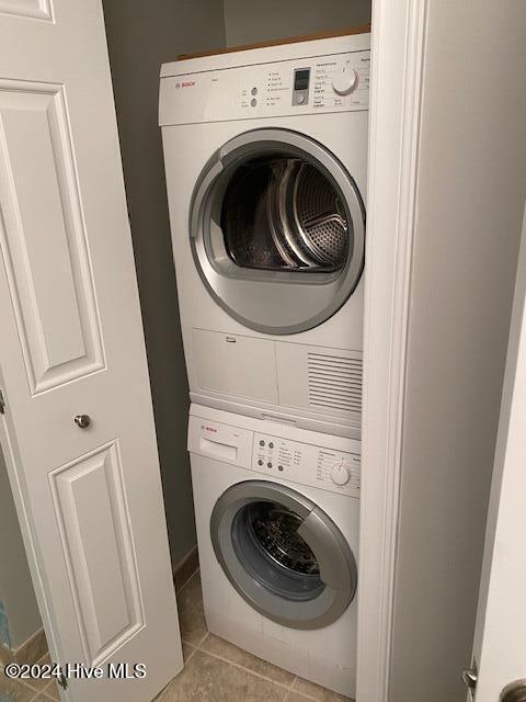 laundry area with light tile patterned floors and stacked washer and clothes dryer