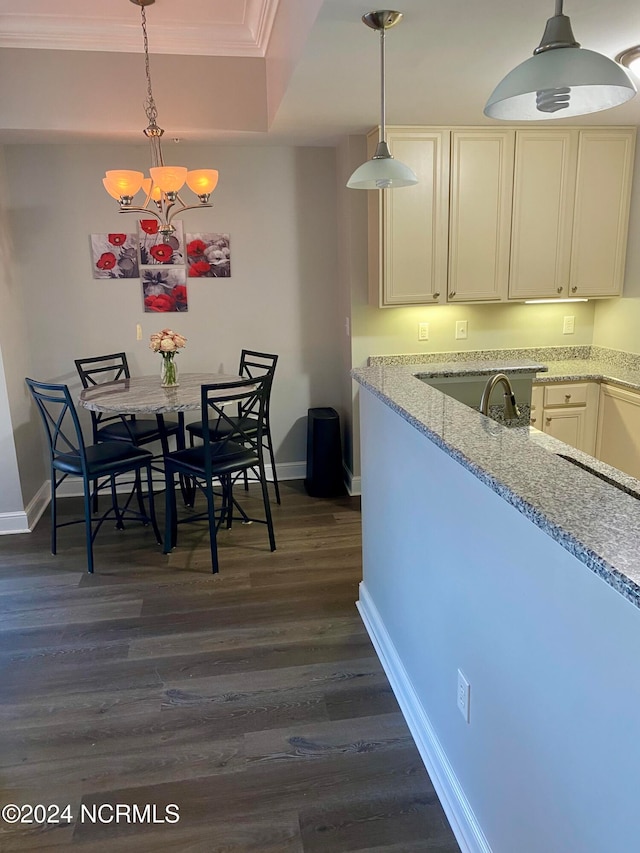 kitchen with pendant lighting, crown molding, dark hardwood / wood-style floors, light stone countertops, and a notable chandelier