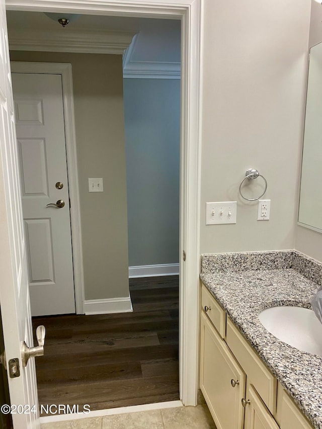 bathroom with vanity, hardwood / wood-style flooring, and crown molding