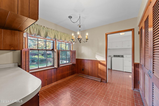 unfurnished dining area with a baseboard radiator, independent washer and dryer, wainscoting, a chandelier, and brick patterned floors