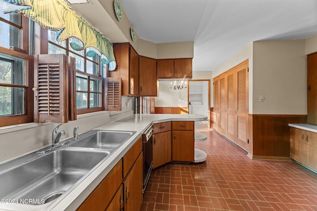 kitchen featuring wood walls, sink, dishwasher, kitchen peninsula, and a chandelier