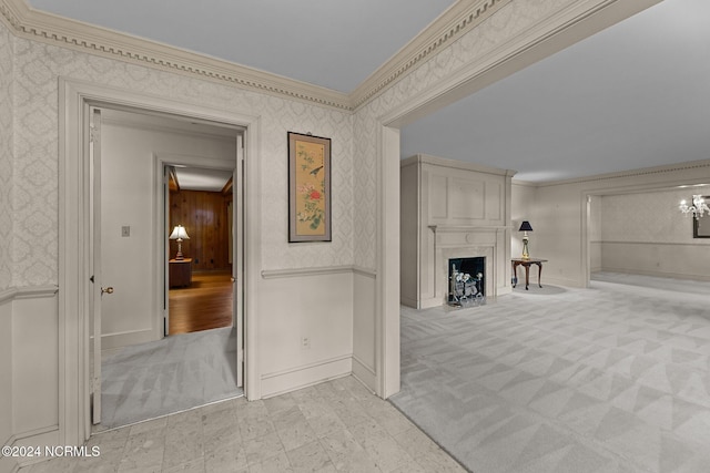unfurnished living room featuring wallpapered walls, ornamental molding, a fireplace, baseboards, and carpet flooring