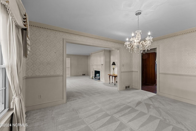 spare room with wallpapered walls, a wainscoted wall, a chandelier, light carpet, and a large fireplace