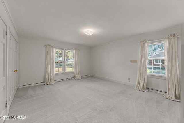 unfurnished bedroom featuring light carpet, multiple windows, ornamental molding, and baseboards