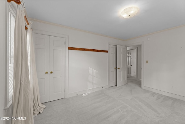 unfurnished bedroom with carpet flooring, crown molding, baseboards, and a closet