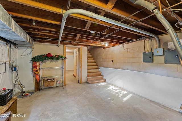 unfinished basement featuring stairs and electric panel