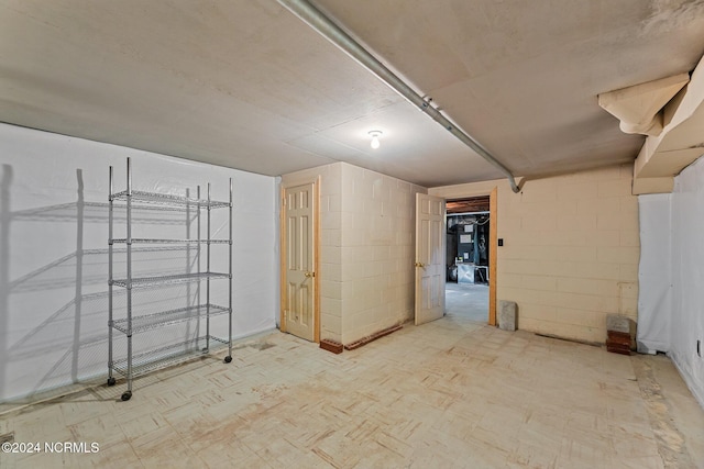 below grade area with tile patterned floors and concrete block wall