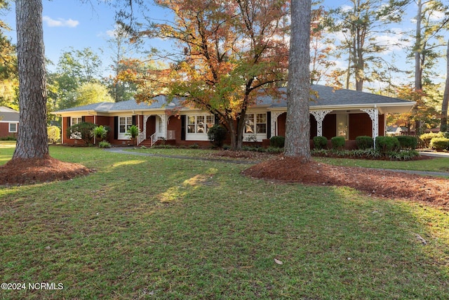 ranch-style house with covered porch, a front yard, and brick siding