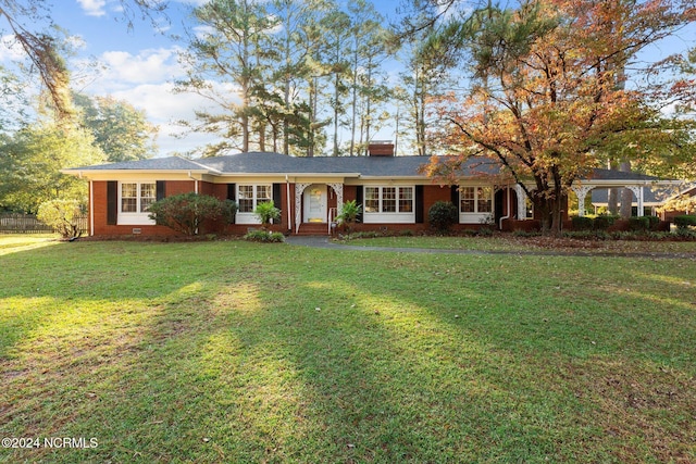 ranch-style house featuring brick siding, a chimney, and a front yard