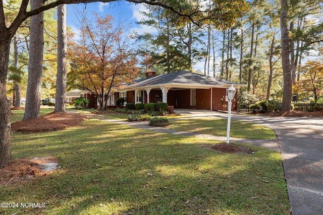 ranch-style house with driveway, a front yard, a chimney, an attached carport, and brick siding