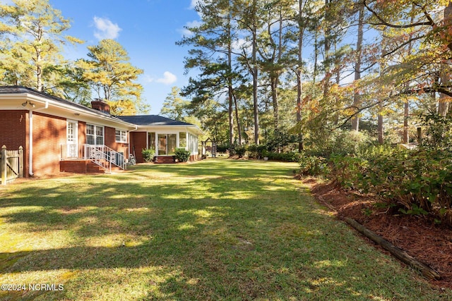 view of grassy yard with a sunroom
