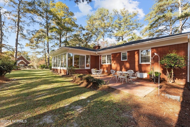 rear view of house with brick siding, a patio, a lawn, and a sunroom