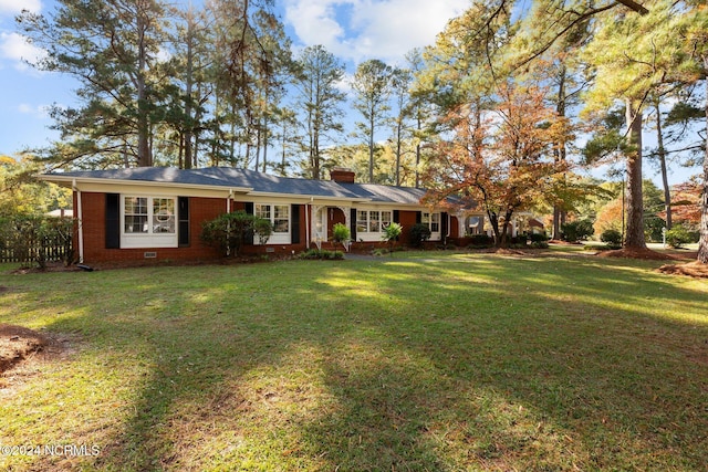 ranch-style home featuring a front lawn, a chimney, and brick siding