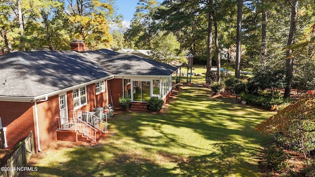 rear view of property with brick siding, a chimney, a shingled roof, a lawn, and central AC unit