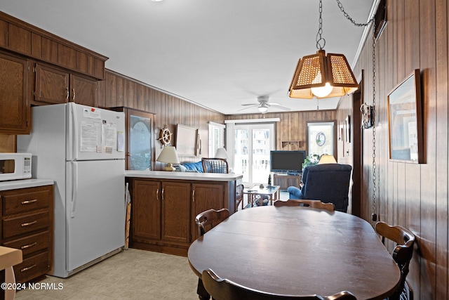 dining area with wooden walls and ceiling fan