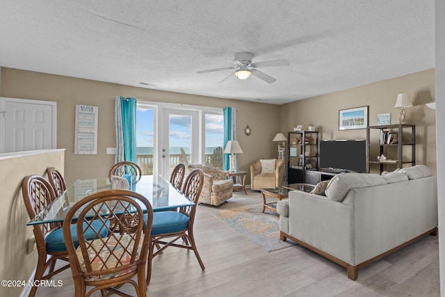 living area with ceiling fan, light wood-style floors, and a textured ceiling