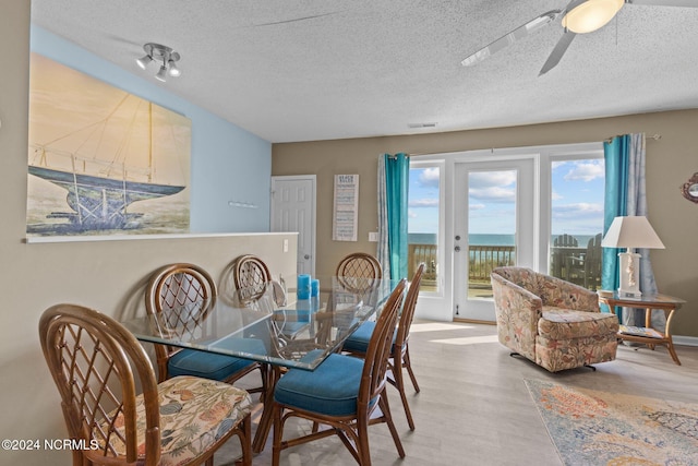 dining room featuring wood finished floors, a textured ceiling, and a ceiling fan