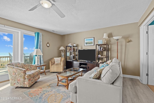 living room featuring a textured ceiling, light hardwood / wood-style floors, and ceiling fan