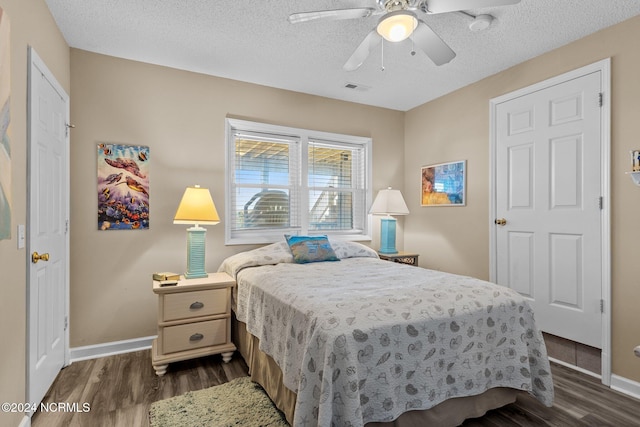 bedroom with dark wood-type flooring, ceiling fan, and a textured ceiling