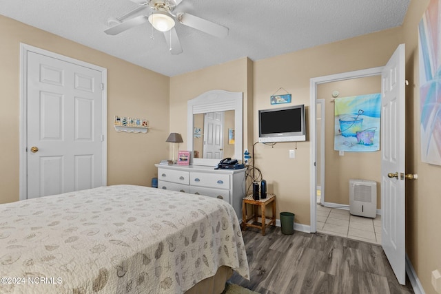 bedroom with ceiling fan, hardwood / wood-style floors, and a textured ceiling