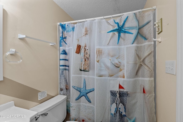 bathroom with a textured ceiling, toilet, and a shower with shower curtain