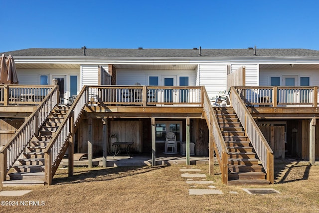rear view of house with stairs, a deck, and a shingled roof
