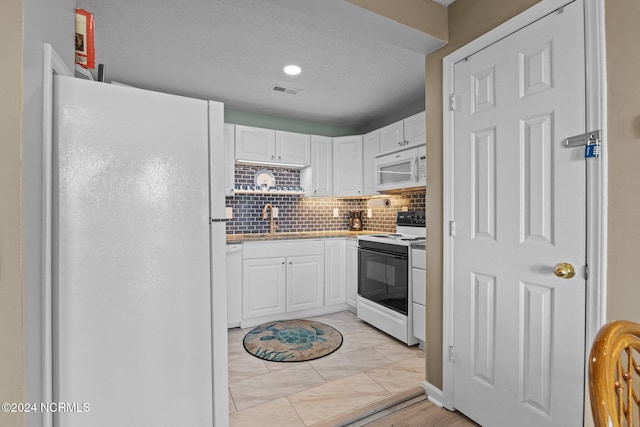 kitchen with white appliances, a sink, white cabinets, and tasteful backsplash