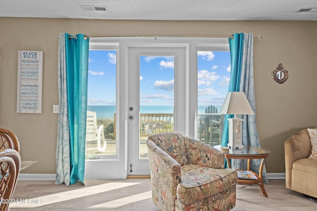 sitting room featuring a water view, baseboards, and wood finished floors