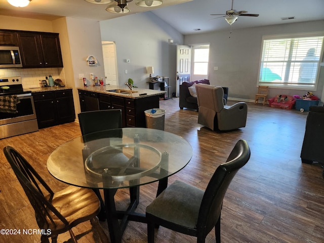 dining space featuring vaulted ceiling, sink, plenty of natural light, and dark hardwood / wood-style flooring