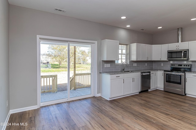 kitchen featuring appliances with stainless steel finishes, tasteful backsplash, sink, hardwood / wood-style flooring, and white cabinetry