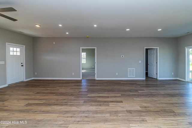 unfurnished room featuring ceiling fan, a healthy amount of sunlight, and dark hardwood / wood-style floors